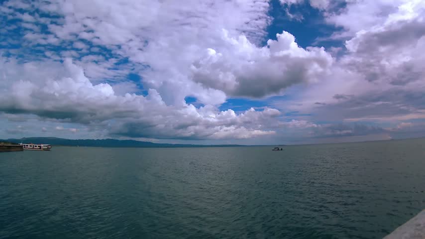 Sea, horizon, island, mountain, embankment. Clouds.