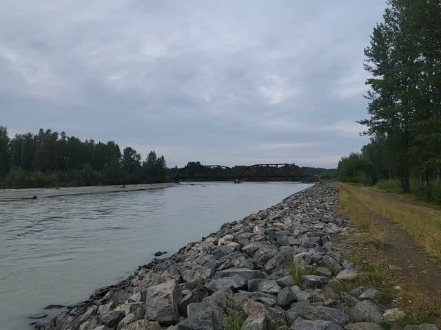 Wide silty glacial river flowing past a gravel bank near a jet boat landing in Talkeetna, Alaska