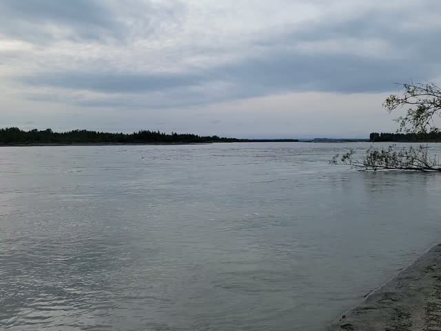 Wide silty glacial river flowing past a gravel bank near a jet boat landing in Talkeetna, Alaska