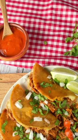 Mexican street food quesabirria tacos served with spicy red salsa bowl and lime on wooden background