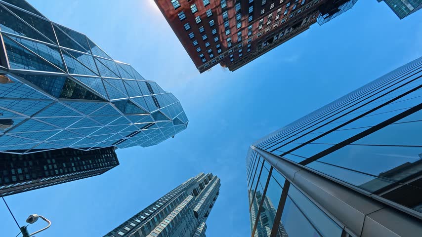 Looking up at the tops of skyscrapers from the street. Low angle view at the high-rises of New York set against blue sky.