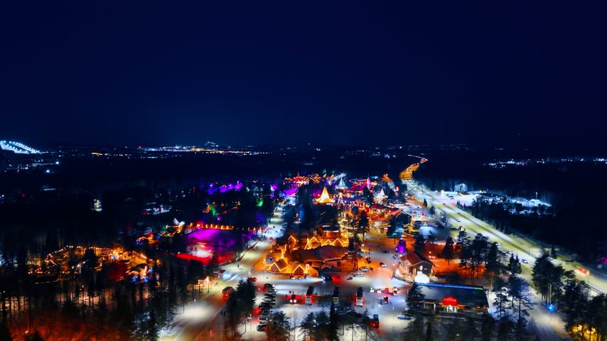 Flying over the luminous scenery of Santa Claus Village at night. Beautiful tourist landmark of Rovaniemi, Finland.