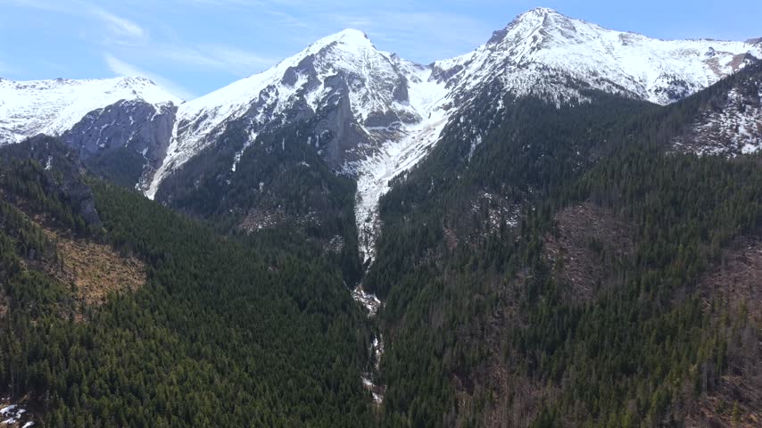Stunning aerial perspective revealing the majestic, snow capped peaks and verdant pine forests of the High Tatras mountain range in Slovakia