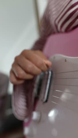 Vertical detail of a woman plucking electric guitar strings