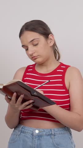 Vertical Shot of Thoughtful Indian Teenage Girl Having a Creative Idea and Writing Notes in a Notebook