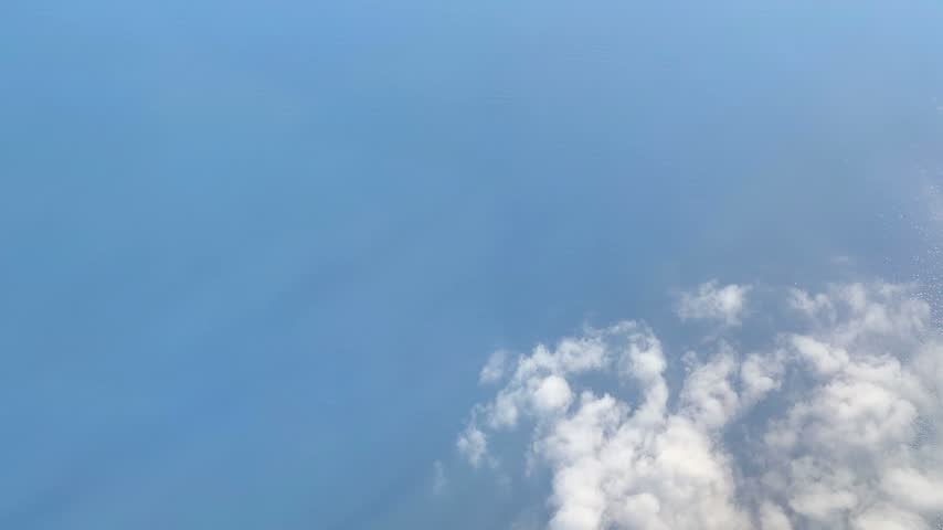 Aerial View of Clouds Floating Above the Sea. Ocean and Cloudscape Viewed from Above the Clouds. Scenic Ocean View Through Clouds from High Altitude.