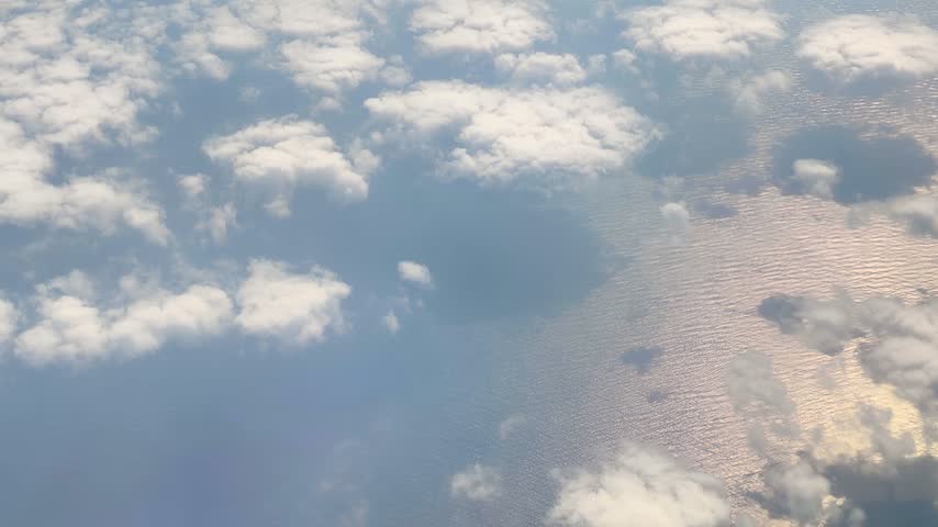 Aerial View of Clouds Floating Above the Sea. Ocean and Cloudscape Viewed from Above the Clouds. Scenic Ocean View Through Clouds from High Altitude.