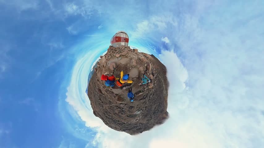 Group of climbers taking a break on the summit of a mountain with a shelter, tiny planet effect