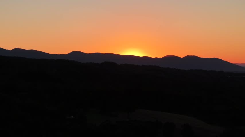 Orange sunset over hills and lake silhouette, aerial, Pucon