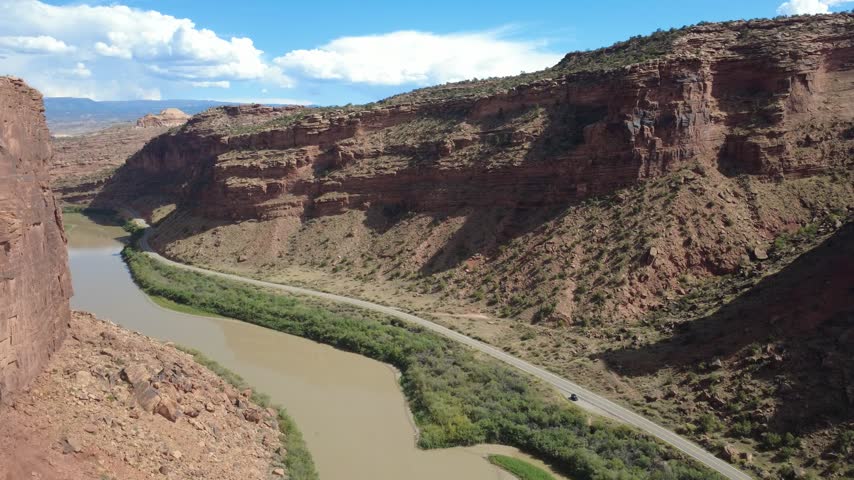 Aerial view of winding river beneath layered sandstone cliffs.