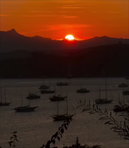 a sunset over a coastal bay with moored boats and hills in the background, in Bodrum in Turkey. 
08.08.2025
