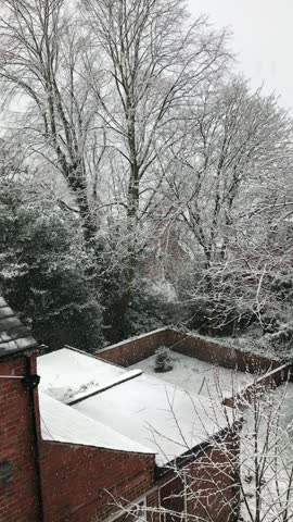 Overlooking a residential road in Forest Fields, Nottingham, lined with traditional English houses as heavy snowfall blankets the neighbourhood, creating a peaceful winter scene.