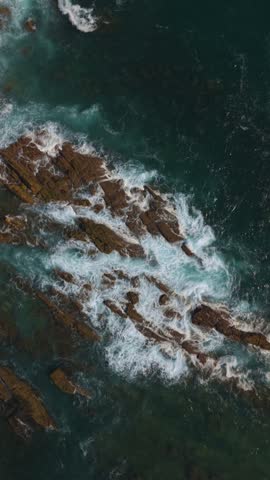 Ocean waves breaking over rocks with rushing foam.