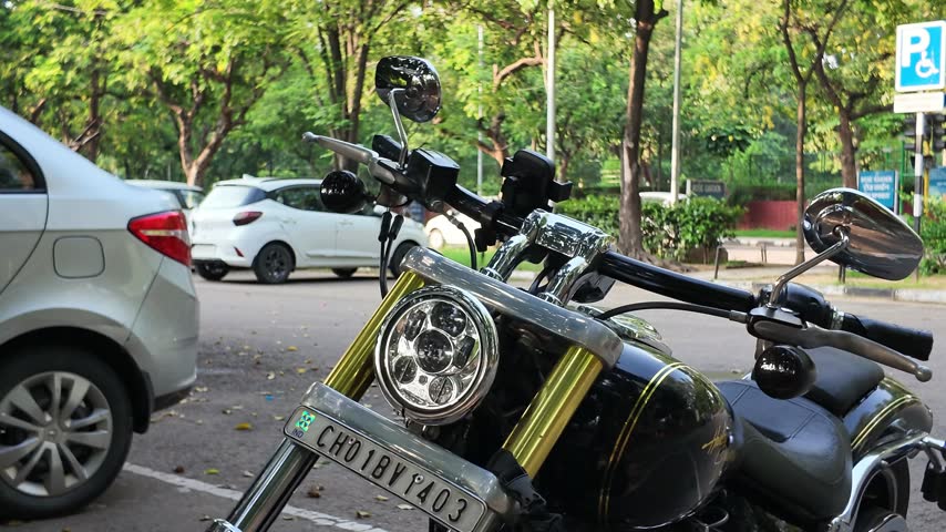Black cruiser motorcycle parked on city street with white car in background