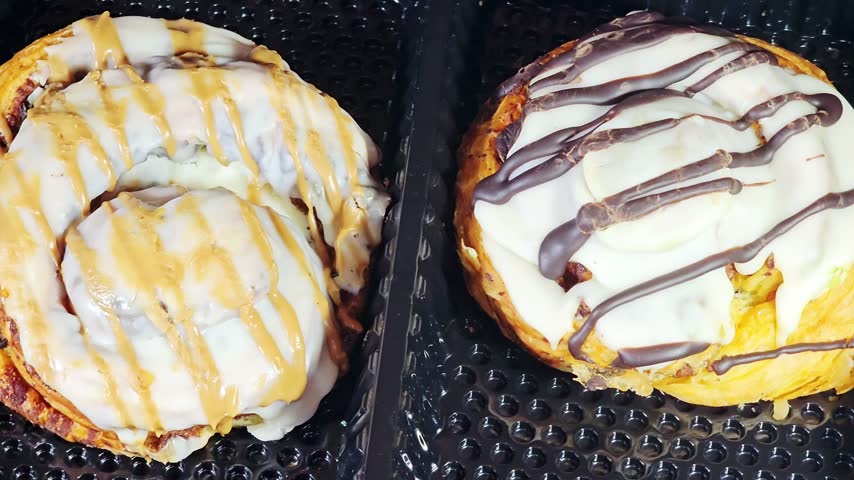 Pastries of a chocolate-drizzled cinnamon roll, a sweet pastry topped with white frosting and dark chocolate stripes, cinnamon roll, a sweet pastry consisting of a rolled sheet of yeast-leavened dough covered in a sweet cinnamon-sugar butter filling, topped with a creamy white icing and a caramel spread drizzle, Danish pastry, a flaky, buttery croissant-style dough base topped with cheesecake icing, a caramel and chocolate drizzle, biscuit cream paste and nuts