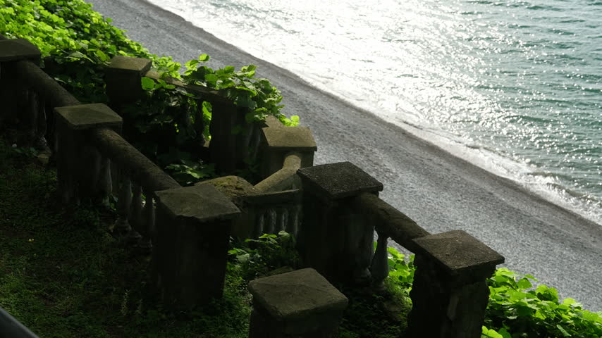 Static high-angle shot overlooking a stone balustrade covered in ivy above the Black Sea beach in Tsikhisdziri Georgia.