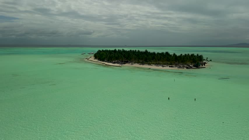 Cinematic aerial view of Onok Island in southern Palawan, Philippines, revealing a pristine white sandy shoreline, shallow mint-green waters, intricate coral reef patterns and a secluded tropical island surrounded by the Sulu Sea.