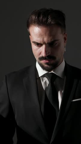 Stylish man adjusting suit and crossing arms getting ready looking forward and side on grey background