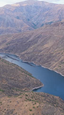 Aerial view of a winding reservoir surrounded by dry, rugged mountain slopes.