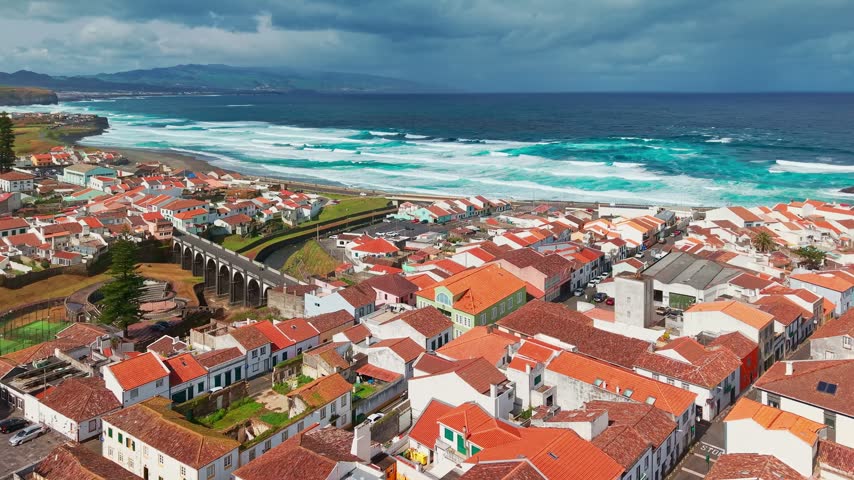Aerial view of Ribeira Grande city on Sao Miguel Island, Azores, Portugal. Traditional white buildings along the Atlantic coast with lush volcanic hills.