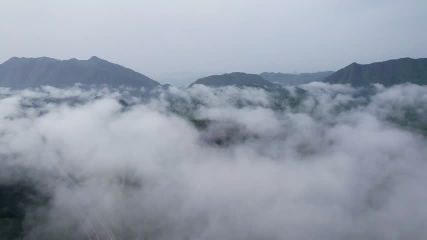 Aerial View of Highway Winding Through Misty Mountains and Thick Sea of Clouds