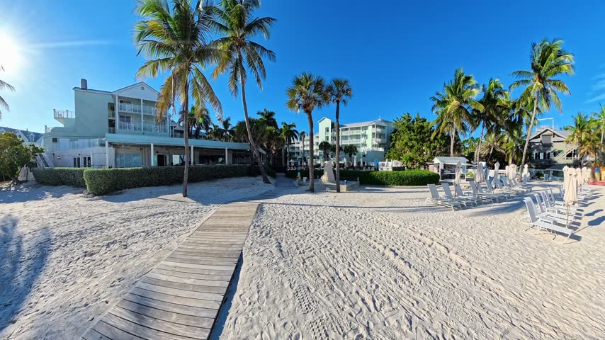 A coastal view reveals beach resort with chairs beside the walkway in Key West Florida.