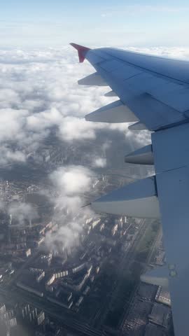 view from the window of an airplane to the wing of an airplane in clear sunny weather, flying over clouds