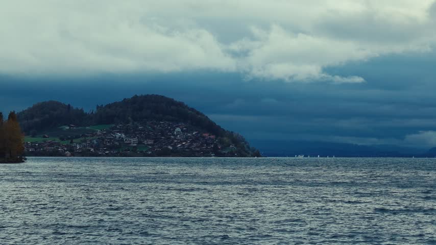 Heavy clouds hang above rippled Brienzer lake water, with a distant mountain shoreline beneath the dark sky.