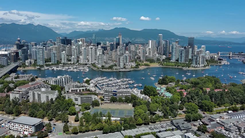 shot of downtown vancouver british columbia showing buildings mountains water false creek bridge blue skies and green trees