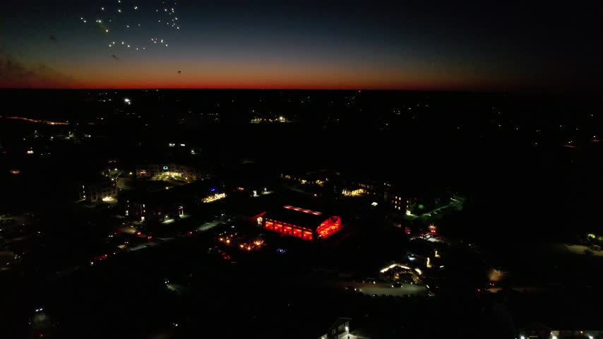 Rising Aerial and Drone shot of Beautiful Fireworks over Pink Sky and activity center in Howard Wisconsin just outside Green Bay.  Dramatic night shots.  