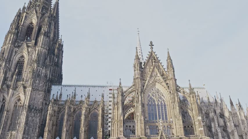 Low angle view of the gothic spires, towers and ornate stone details of the landmark Cologne Cathedral (Kolner Dom) against a bright sky in Cologne, Germany