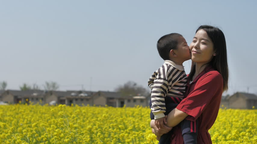 Chinese mother and child blowing bubbles in rapeseed field