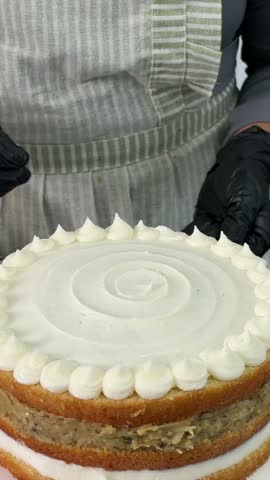 Decorating a vanilla pistachio naked cake with chopped pistachios on buttercream border