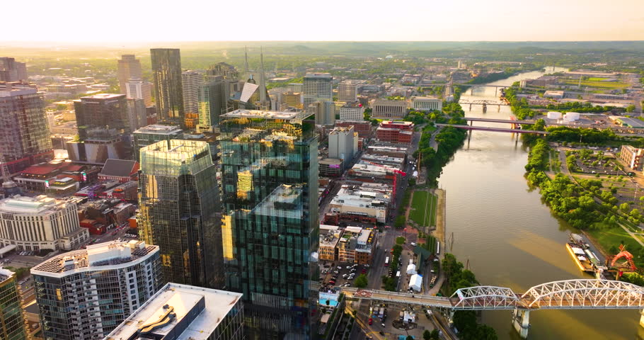 Nashville city urban environment in Tennessee, USA at sundown time. View from above of skyscraper district with riverfront bridge in evening atmosphere.
