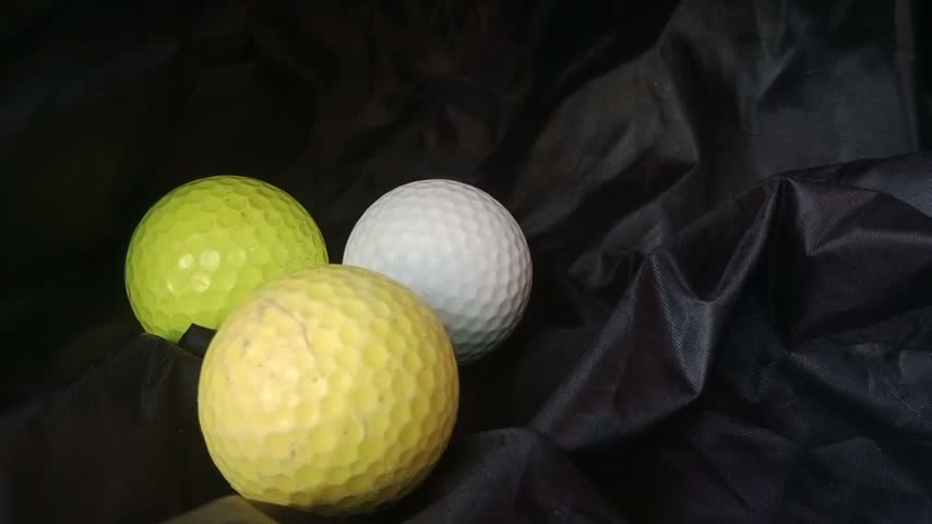 Picking up three colorful golf balls on top of black plastic