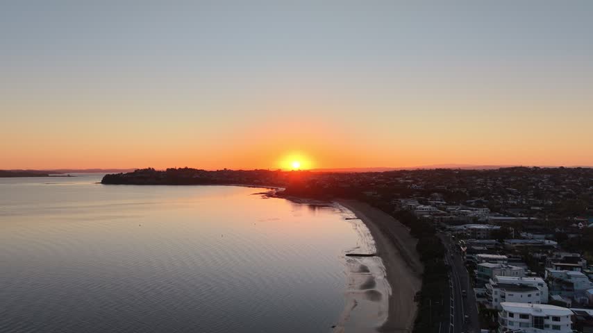 Aerial view of curved bay and beach at sunrise with coastal suburb, eastern bays, Auckland, New Zealand