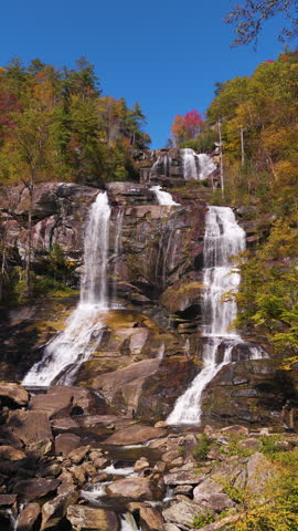 Scenic Whitewater Falls near Cullasaja River surrounded by vibrant fall foliage and lush woodland. Rushing water creates majestic Appalachian landscape.