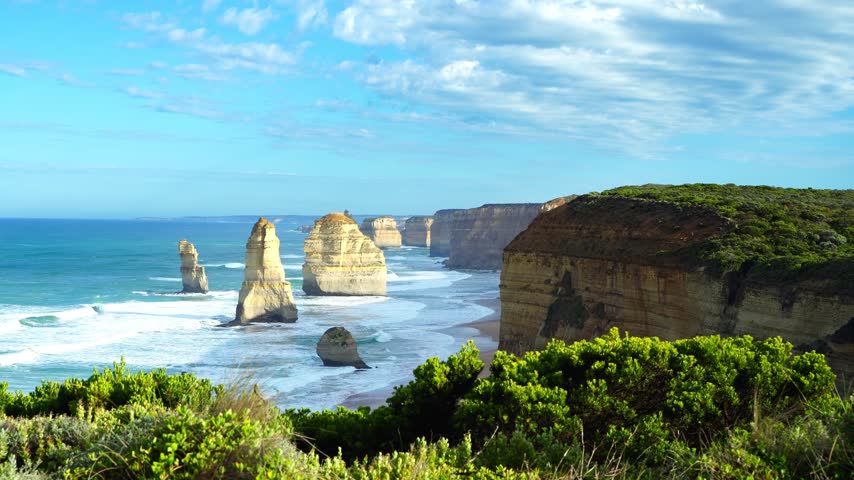 Twelve Apostles at dawn with golden sunlight and rolling ocean waves, Victoria, Australia