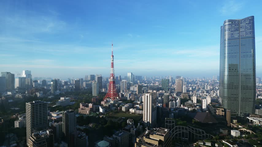 Japan city travel timelapse: early morning haze slowly clears over central Tokyo while thin clouds drift past a red communication tower and a tall glass office skyscraper above dense blocks