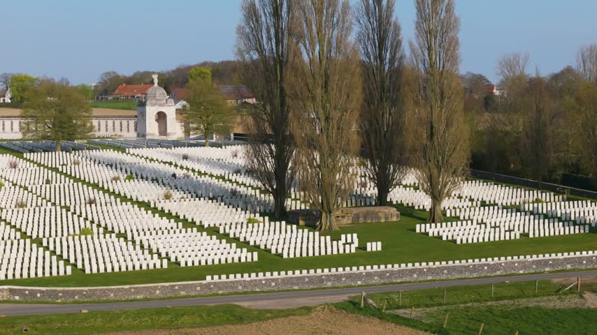 war graves cemetery tyne cot aerial close section geometric rows white wwi gravestones beneath tall trees cross of sacrifice zonnebeke belgium flanders remembrance armistice pilgrimage site 1917
