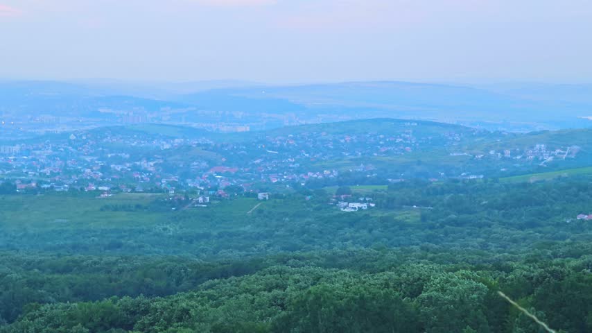 Panoramic city view of Iasi, Romania, seen from Repedea Hill during sunset with rain shafts in the distance. Ideal for landscape stock themes.