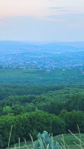 Panoramic city view of Iasi, Romania, seen from Repedea Hill during sunset with rain shafts in the distance. Ideal for landscape stock themes.