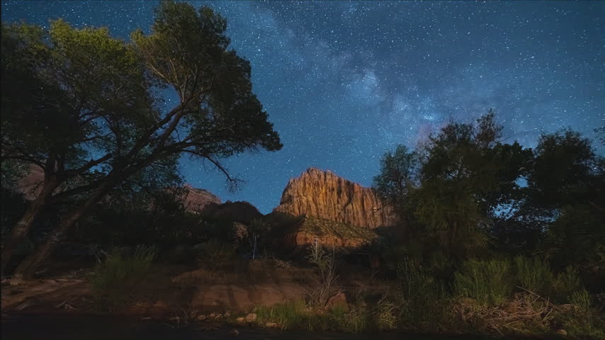 Time-lapse of stars over red rock cliffs in Zion National Park on a summer night.