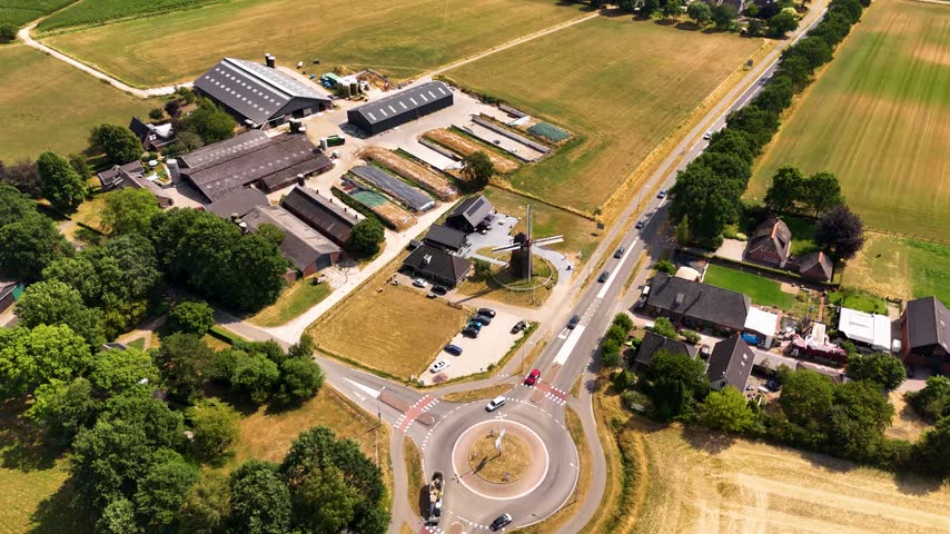 Aerial footage of a roundabout and rural farm in summer.