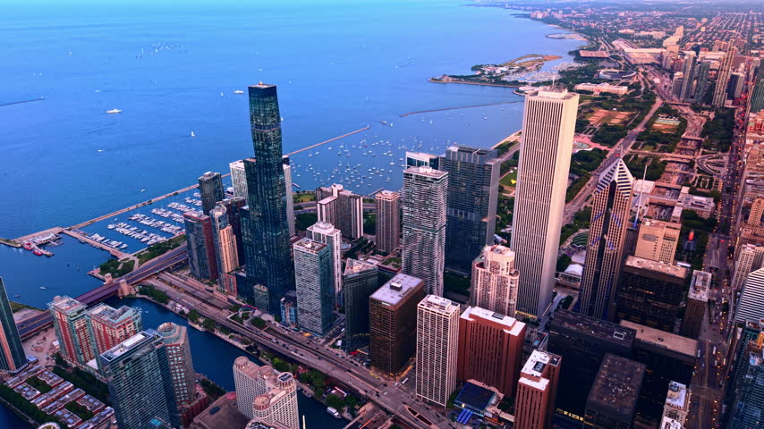 Coastal harbor and lakefront high-rises at dusk, Chicago. Marina harbor filled with boats, lakefront park, tall office towers and dusk sky.