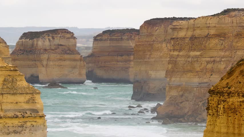 Limestone sea stacks surrounded by ocean surf on Australian coastline. Scenic coastal landscape with rocky cliffs and sea.