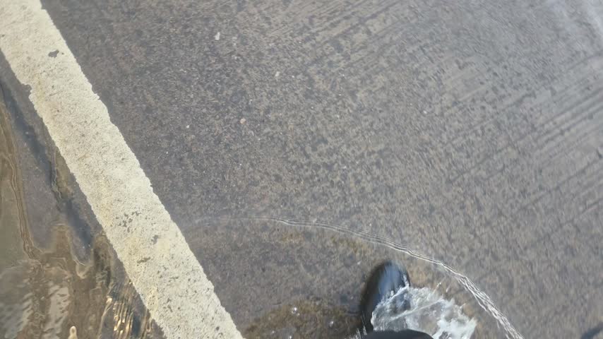 Person Walking in Waterproof Boots Splashing Through Rain Puddle	
