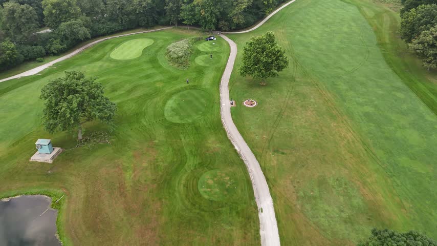 Drone view of golf course fairways, greens and a winding cart path surrounded by mature trees. Filmed in River Grove, Illinois.