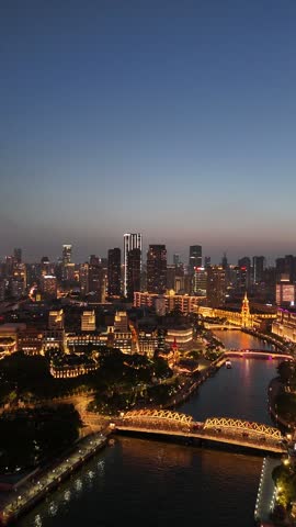 Aerial night view of Shanghai skyline along Suzhou Creek, illuminated modern skyscrapers and historic architecture, China.
