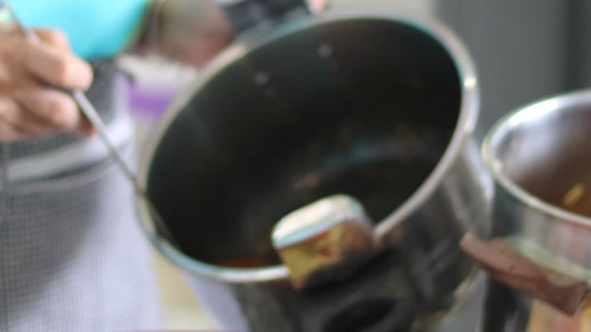 Ladle pouring broth over Moroccan couscous topped with tfaya, chickpeas, meat and vegetables in a traditional terracotta dish